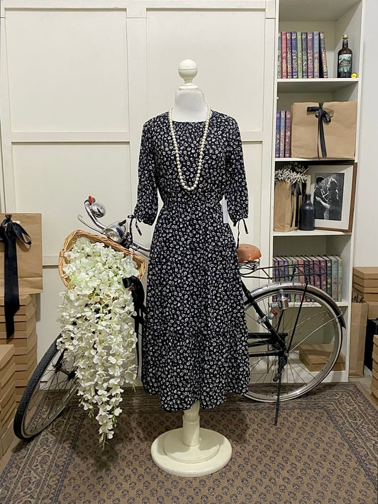 Melania, vestido midi línea A negro flores manga semi larga